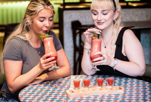 two ladies with strawberry daiquiris and margarita shots at revolución de cuba