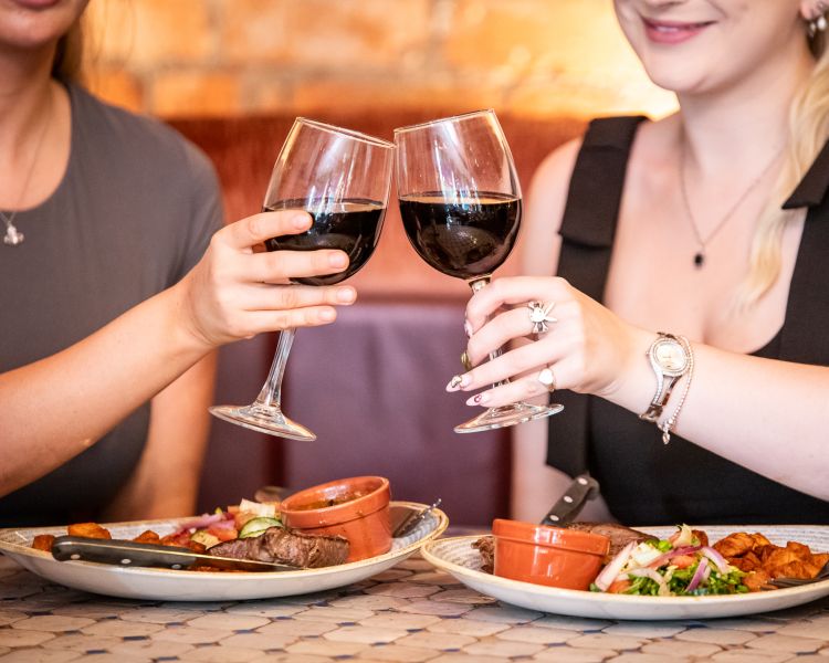 two ladies enjoying a steak meal and bottle of house wine at revolución de cuba