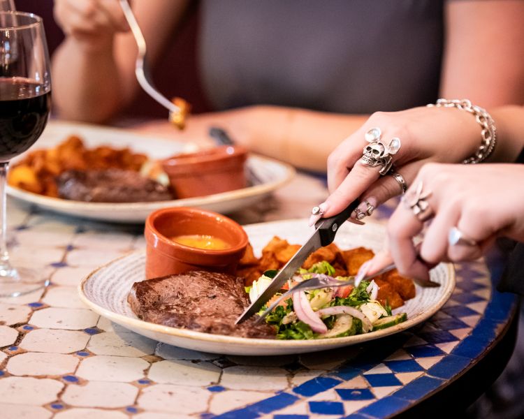 two ladies enjoying a steak meal and bottle of house wine at revolución de cuba
