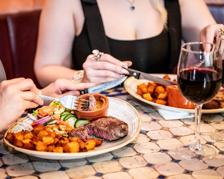 two ladies enjoying a steak meal and bottle of house wine at revolución de cuba