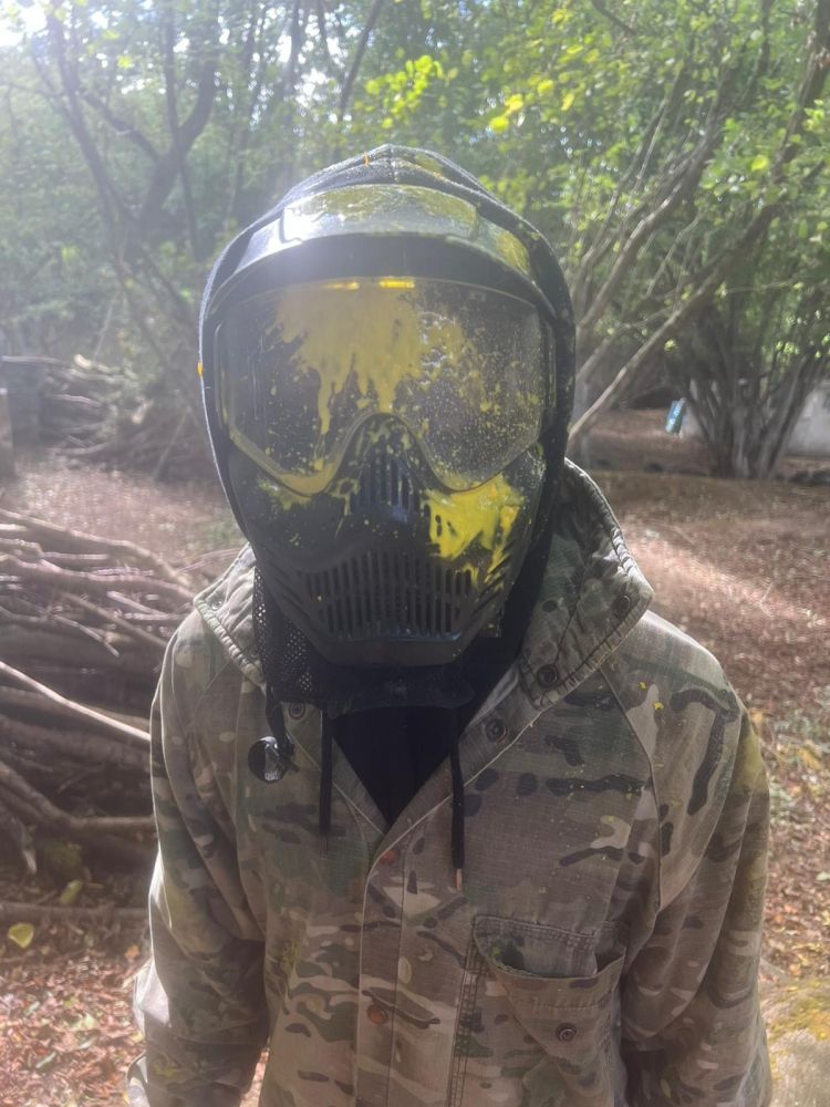 Person with paint splattered on helmet playing paintball