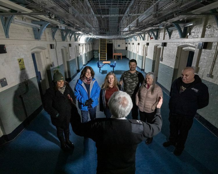 group of people listening to a prison guard on a night behind bars experience