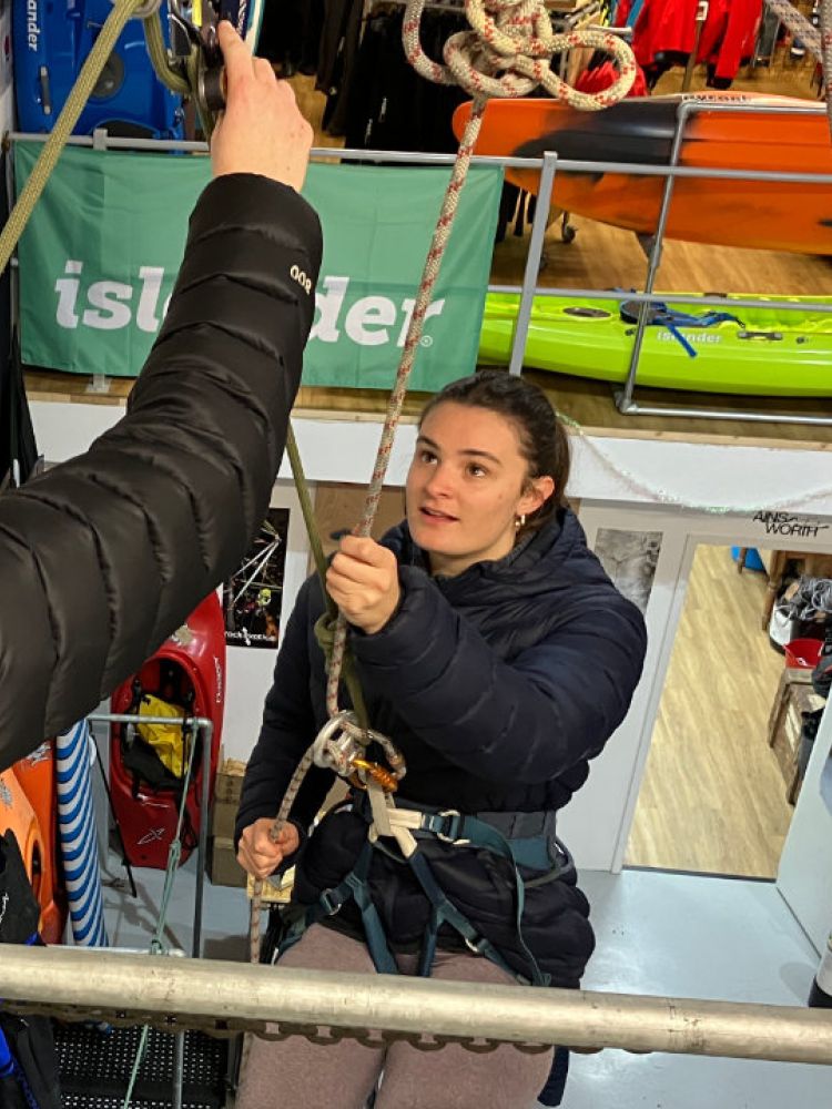 woman about to abseil down an indoor wall with instructor looking on on an abseiling taster session in brighton