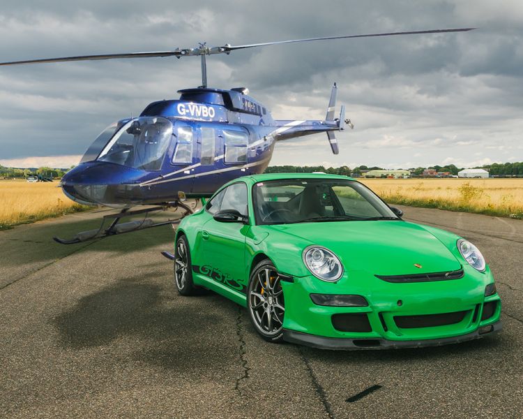 a green sports car on a track with a helicopter behind it for a fly and drive experience day