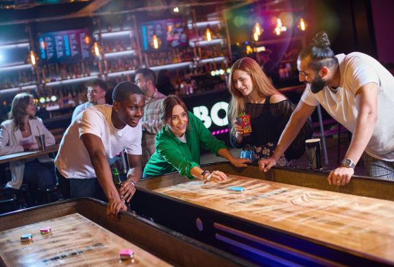 friends playing shuffleboard at a boom battle bar