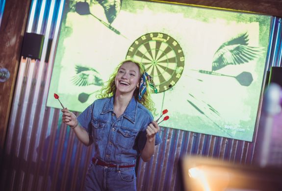 woman playing darts at a boom battle bar