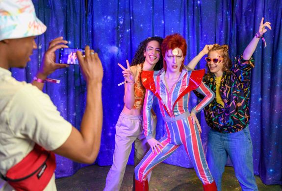 Guests pose for a picture with David Bowie figure at Madame Tussauds London