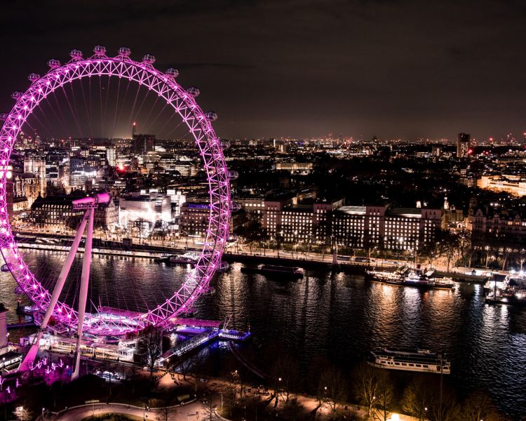 aerial view of the london eye lit up in pink at night
