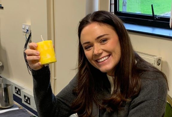 Woman smiling holding the candle she has made at candle making workshop