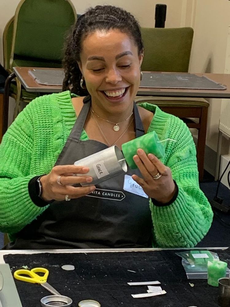 Woman removing candle from mould at candle making workshop