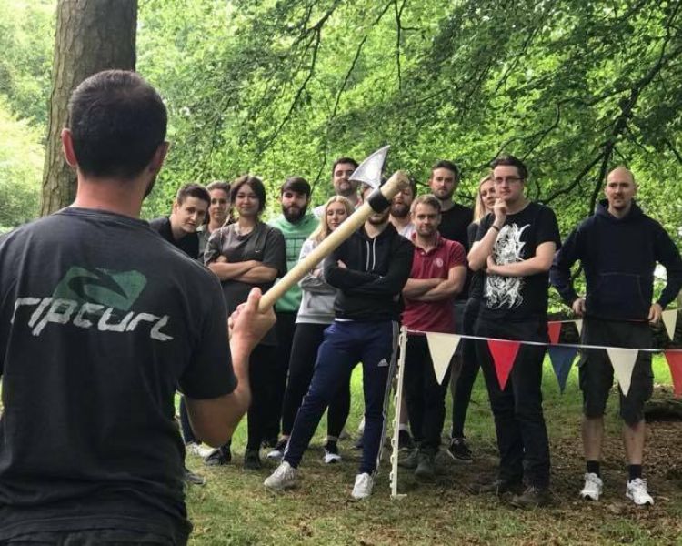 instructor explaining how to throw an axe to a group of people on an axe throwing experience day
