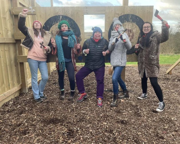 Women posing with axes on an axe throwing experience