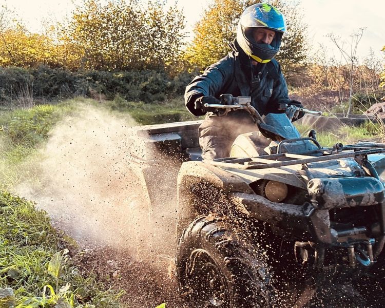 man riding quad bike through water in devon