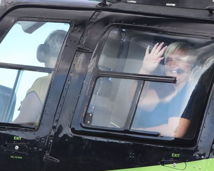 person waving from inside a helicopter about to take off for a helicopter ride