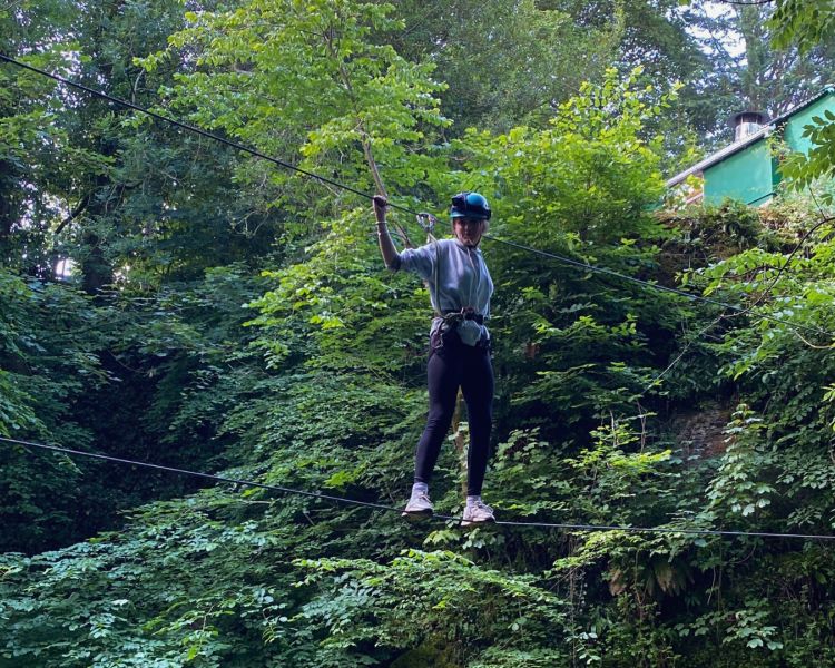 person walking along a high wire through a forest