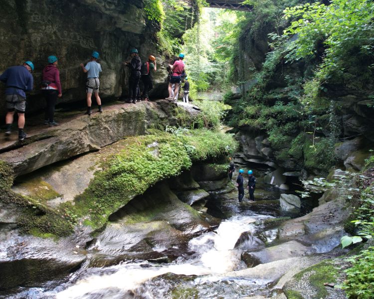 people walking along the edge of a gorge overlooking a river