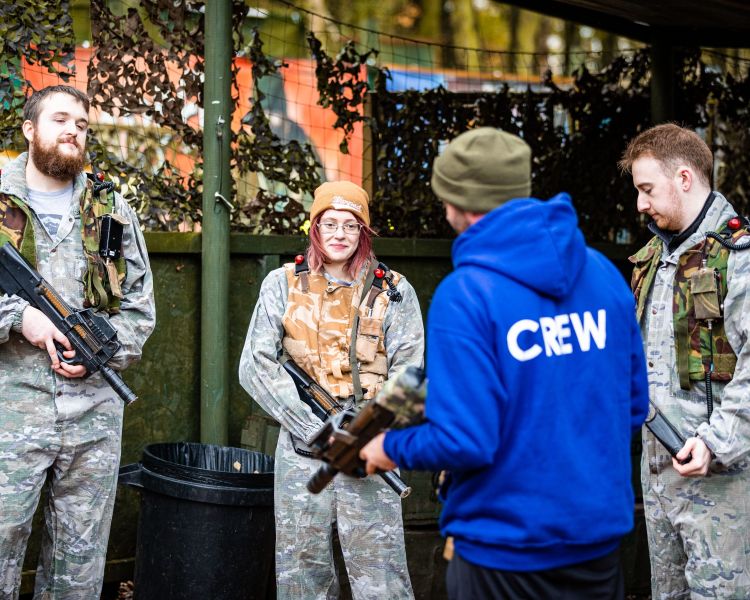crew member talking to group on outdoor laser combat experience in woodland