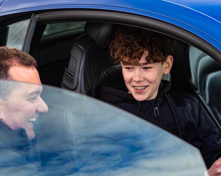 teenage boy in supercar with instructor on family driving day