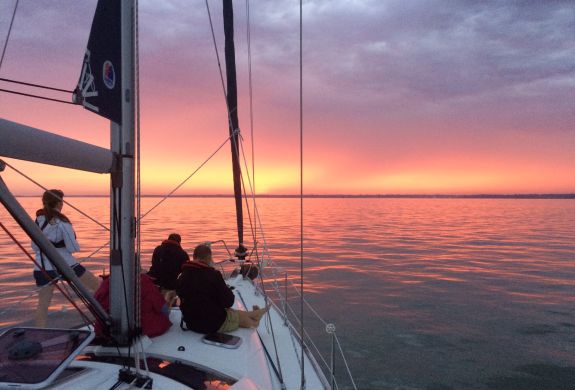 people sitting at front of yacht on the solent at sunset
