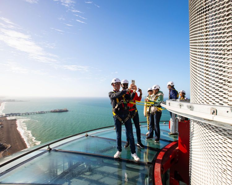 people taking selfies while on the i360 sky walk in brighton