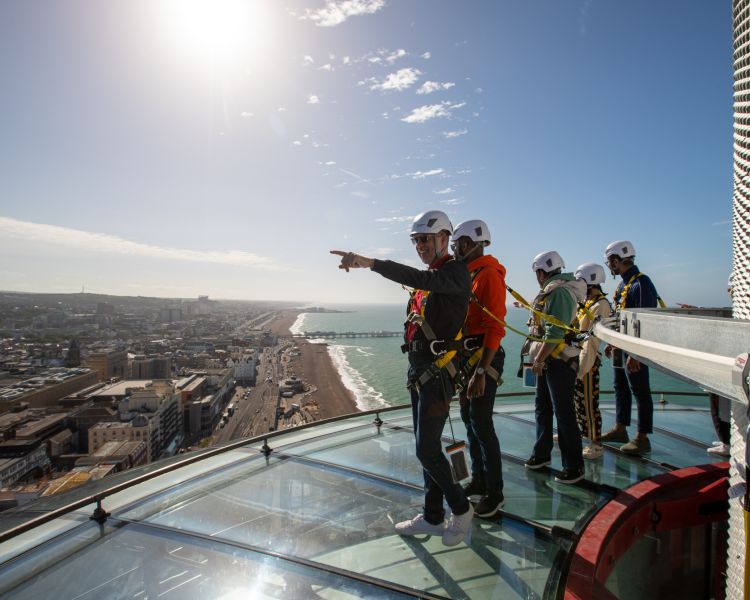 people on the i360 sky walk looking at the sights over brighton
