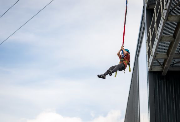 person jumping off the side of a building doing the leap of faith at adventure activity centre in wales