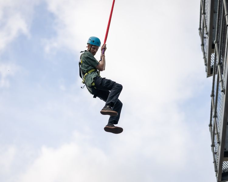 person hanging off the side of a building doing the leap of faith at adventure activity centre in wales