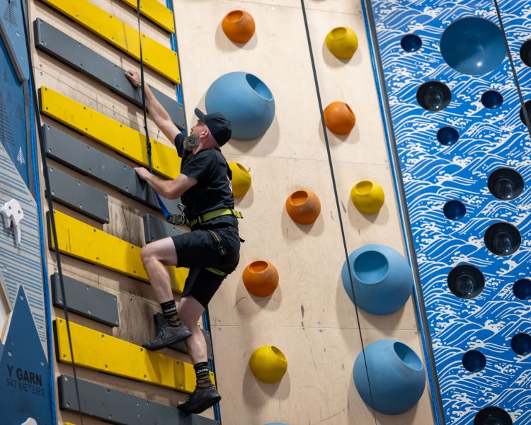 man on climbing wall at adventure climb experience in wales