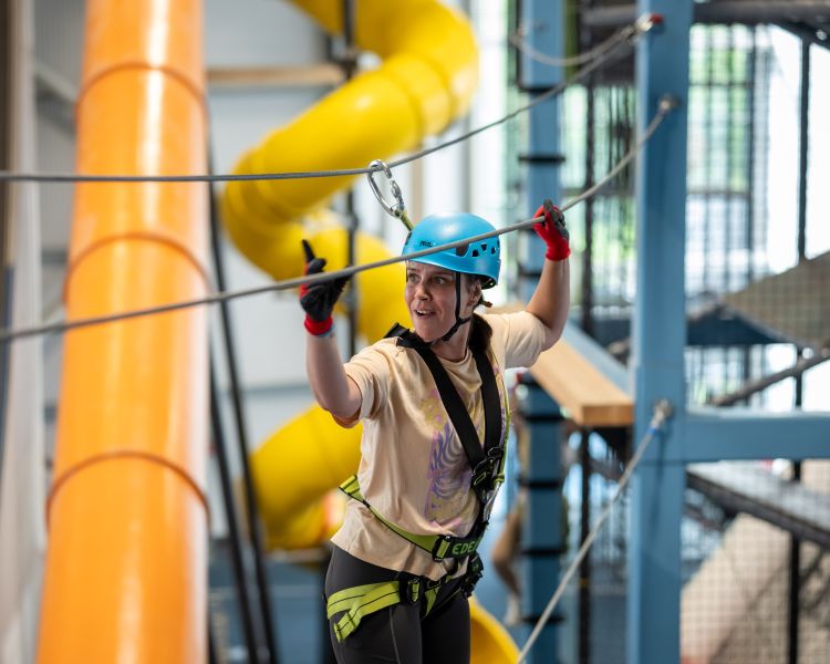 girl walking on indoor high ropes course at activity centre in wales