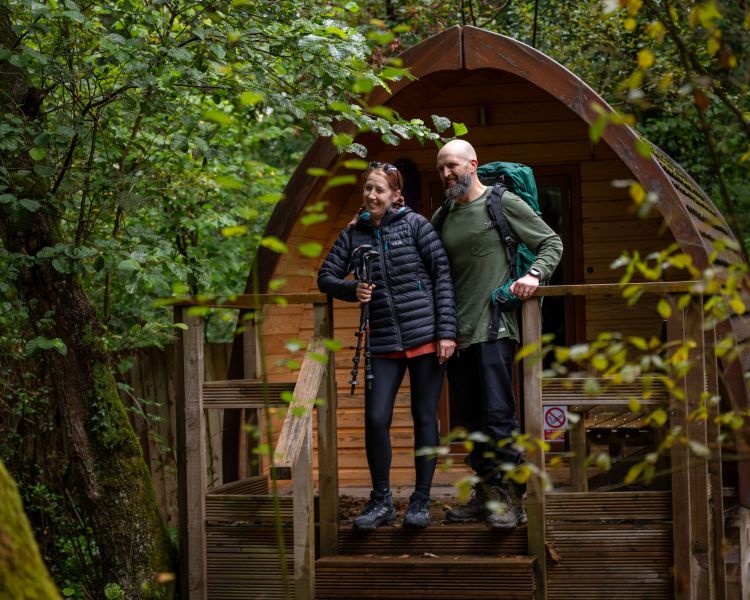 couple outside wooden pod at activity centre in wales for overnight stay