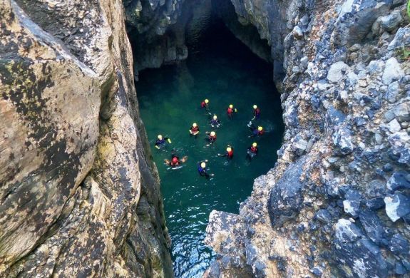 Group in water in sea cave on coasteering experience in pembrokeshire