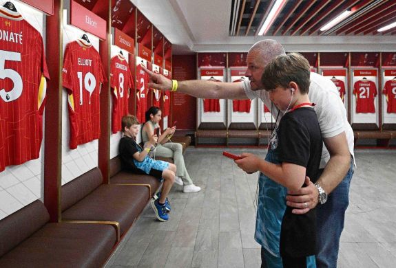 A father and son exploring the dressing room with audio guide