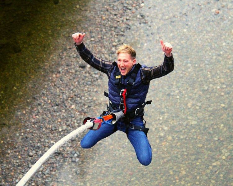 man doing a bungee jump over a river on a bungee jump experience day
