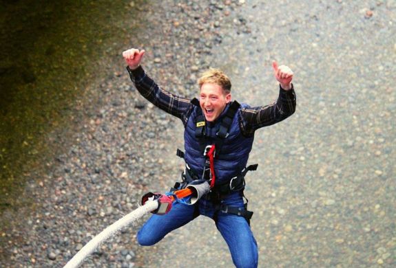 man doing a bungee jump over a river on a bungee jump experience day