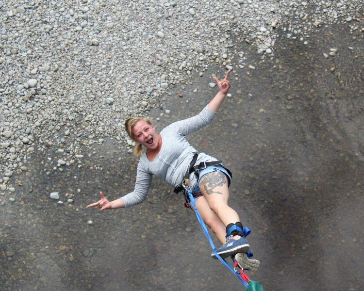 woman doing a bungee jump over a river on a bungee jump experience day