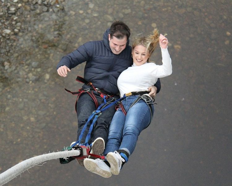 couple doing a tandem bungee jump over a river on a bungee jump experience day