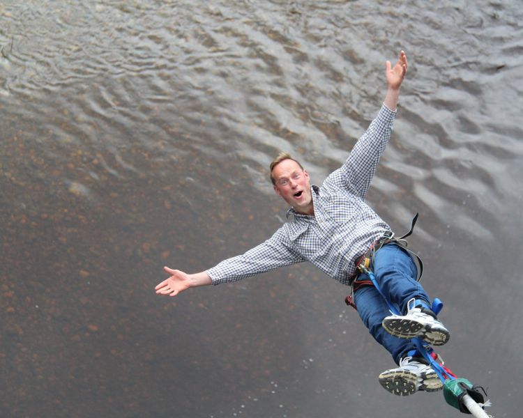 man doing a bungee jump over a river on a bungee jump experience day