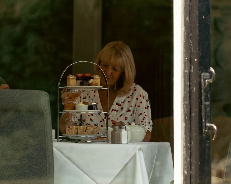 Looking through window at lady having afternoon tea at grinkle park