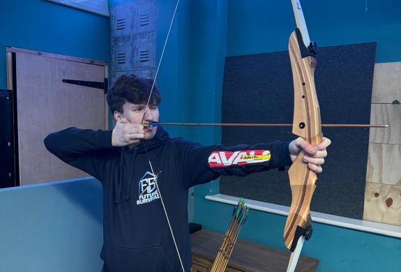 An instructor aiming a bow indoor archery