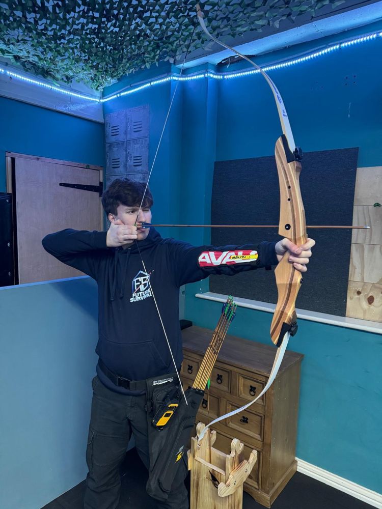 An instructor aiming a bow indoor archery