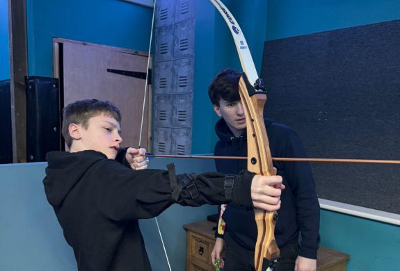 An instructor and young boy indoor archery