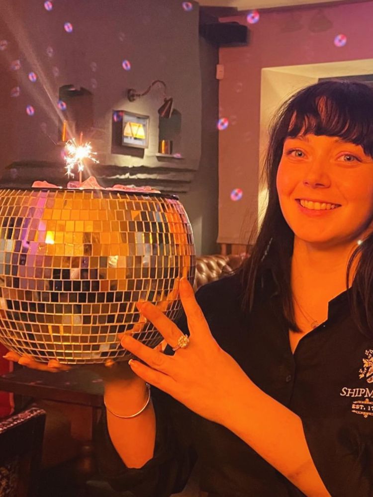 A staff member holding a disco ball cocktail