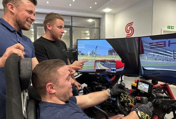 Men stood by a driving sim
