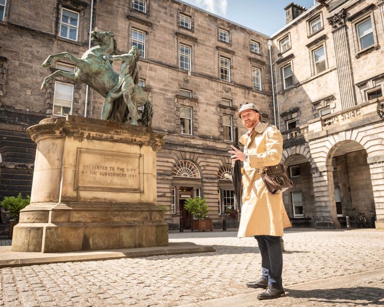 guide standing next to statue on an historical walking tour of edinburgh