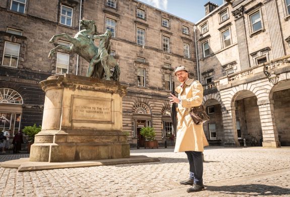 guide standing next to statue on an historical walking tour of edinburgh
