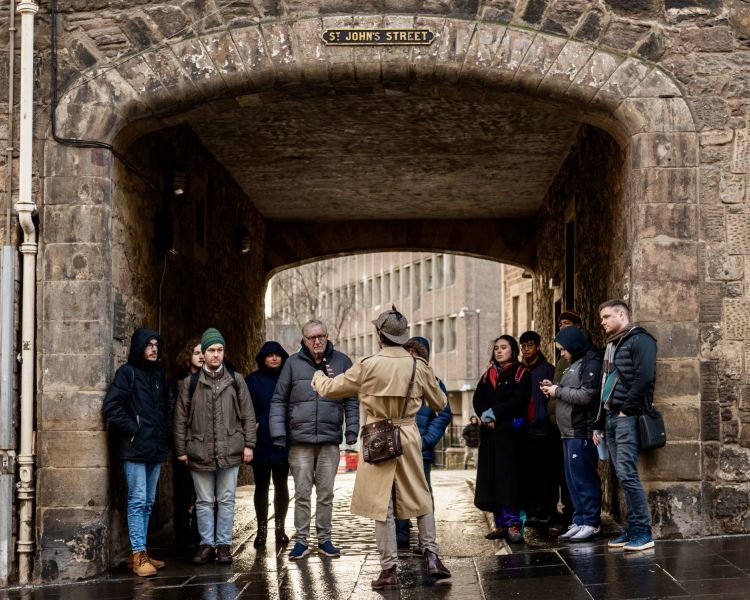 guide talking to group under archway on a historical walking tour in edinburgh