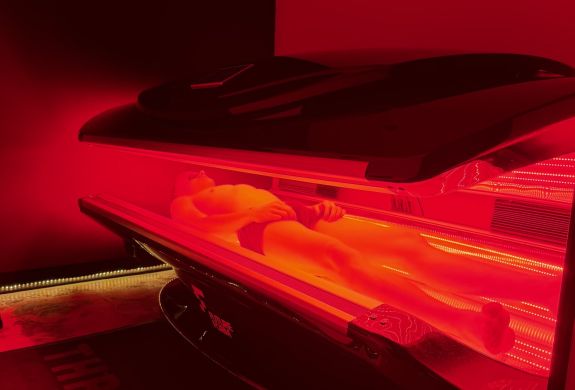 Person lying in red light therapy bed for treatment at thriyv in manchester