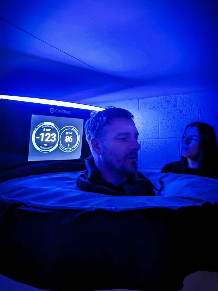 Man inside cryotherapy chamber with head exposed and temperature on screen