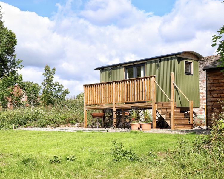 a green shepherds hut in the walled garden of a shropshire estate