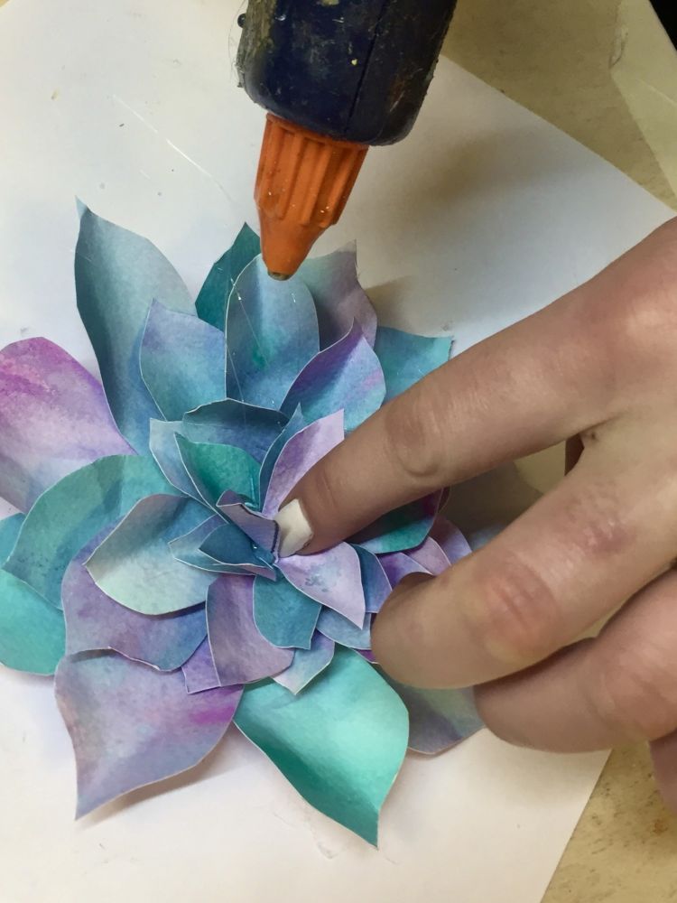 glueing flower petals together to make a paper flower on a craft workshop
